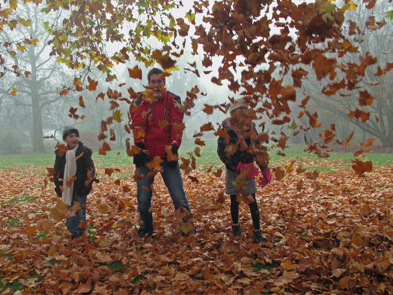 kinderen gooien herfstbladeren